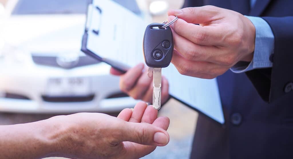 Zoomed in photo of a person handing over car keys to another person